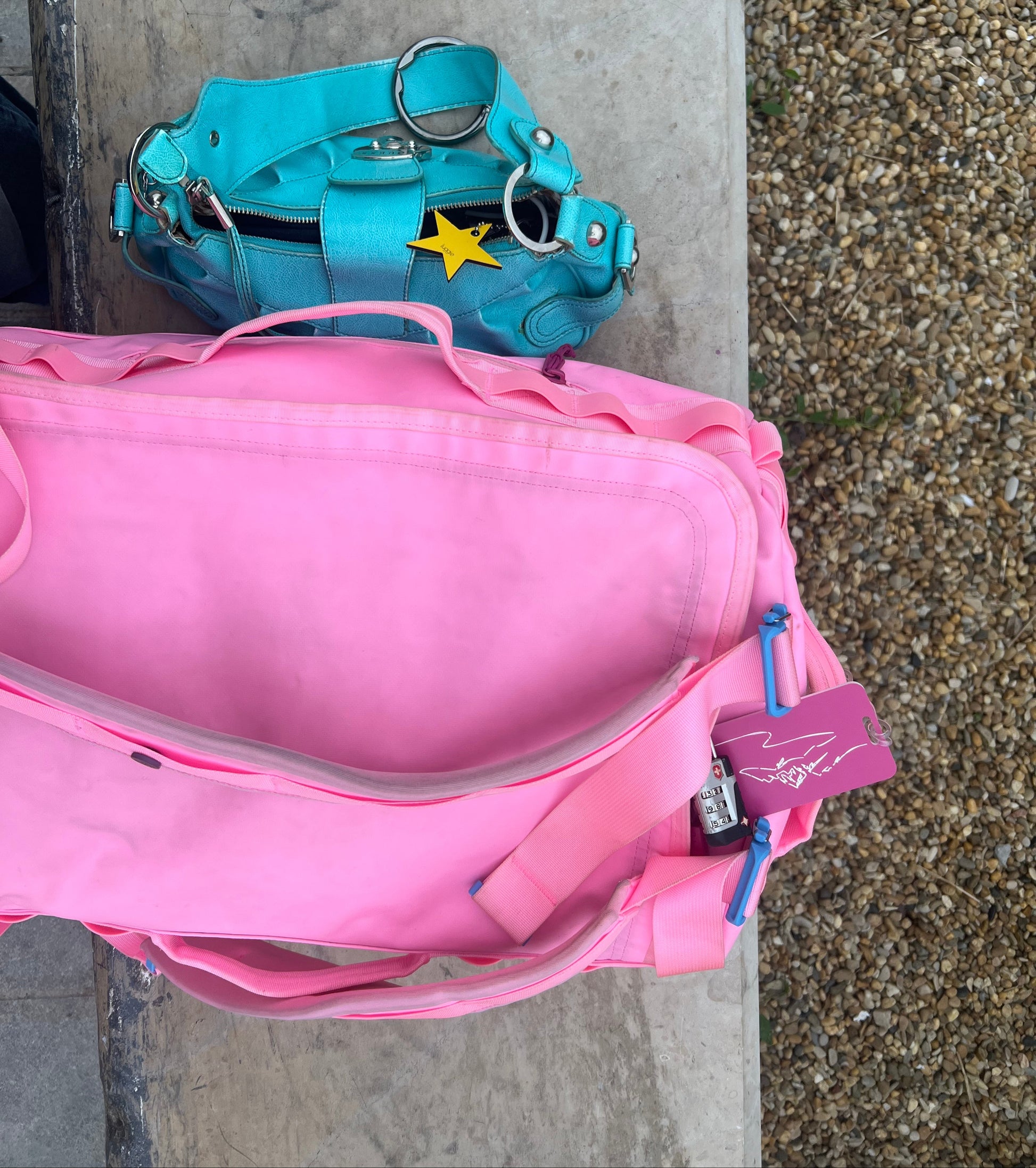 Summit Design Luggage Tag in pink attached to pink bag with blue bag and star keychain in background.