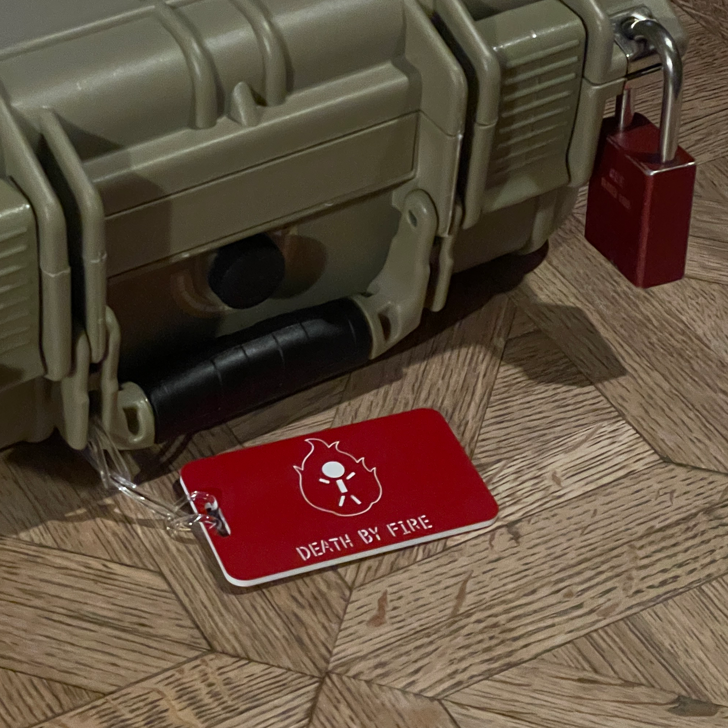 Green hard-shell travel case with a red custom luggage tag and lock on a wooden floor