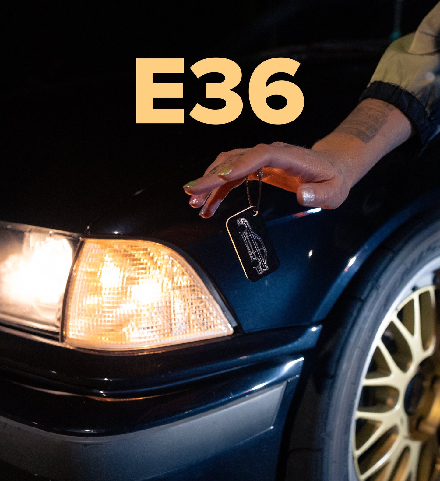 Photo of E36 M3 keychain in front of a black e36 m3 on bbs wheels.