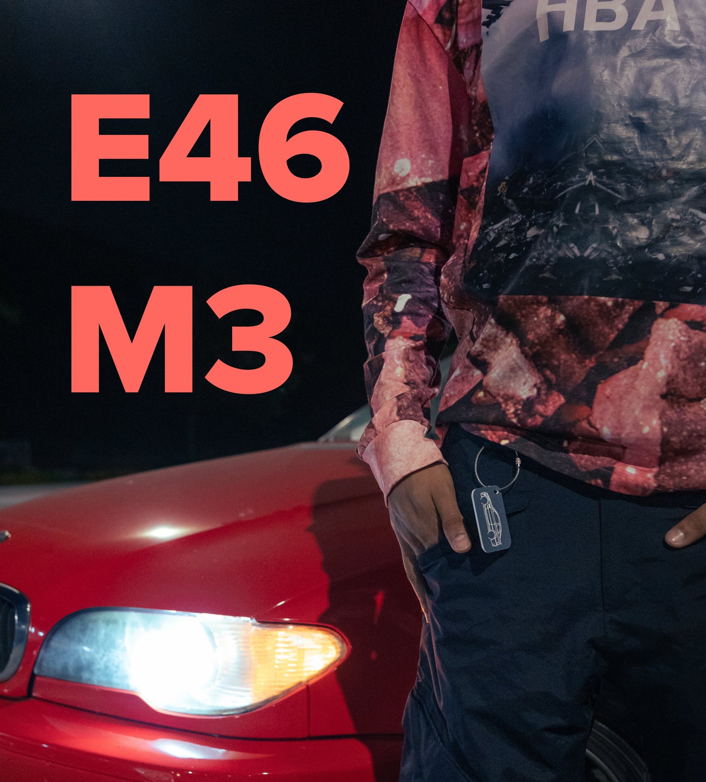 Model standing with E46 M3 Keychain in grey in front of a red E46.