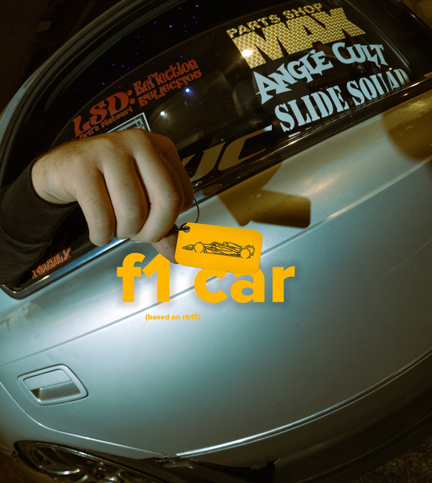 Picture of F1 car Acrylic Keychain in yellow with drift car in background.