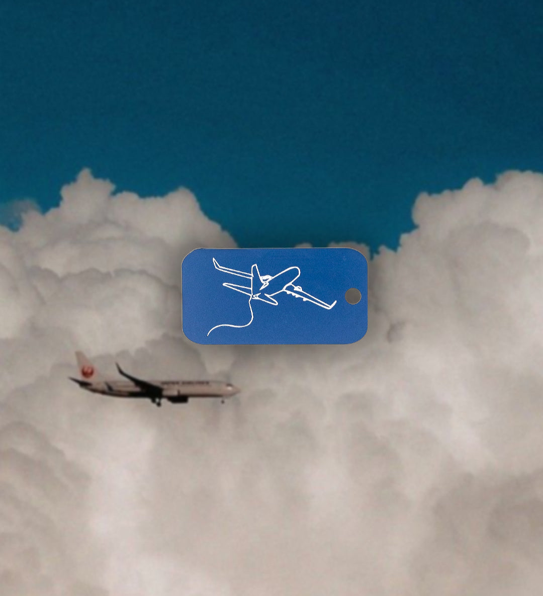 Airplane design keychain in light blue in front of airplane flying.