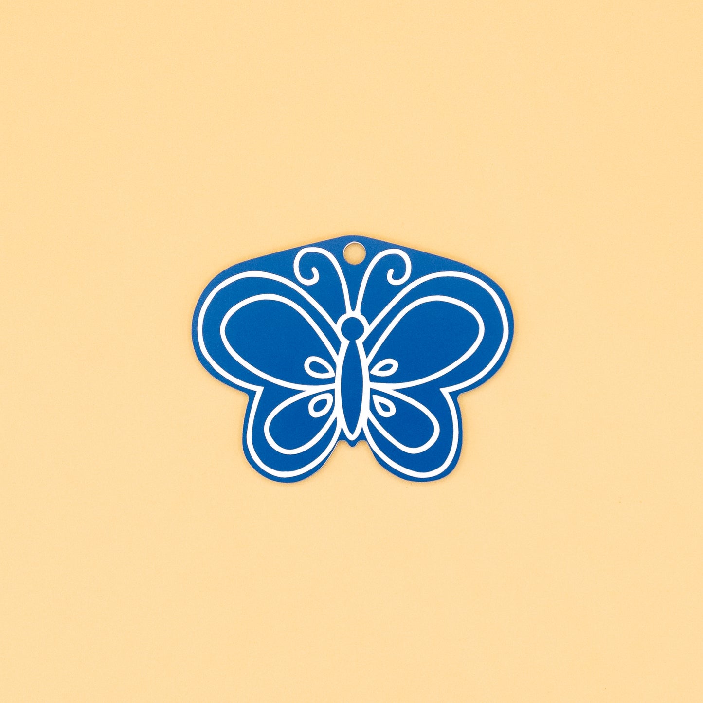 Blue butterfly-shaped keychain on a beige background