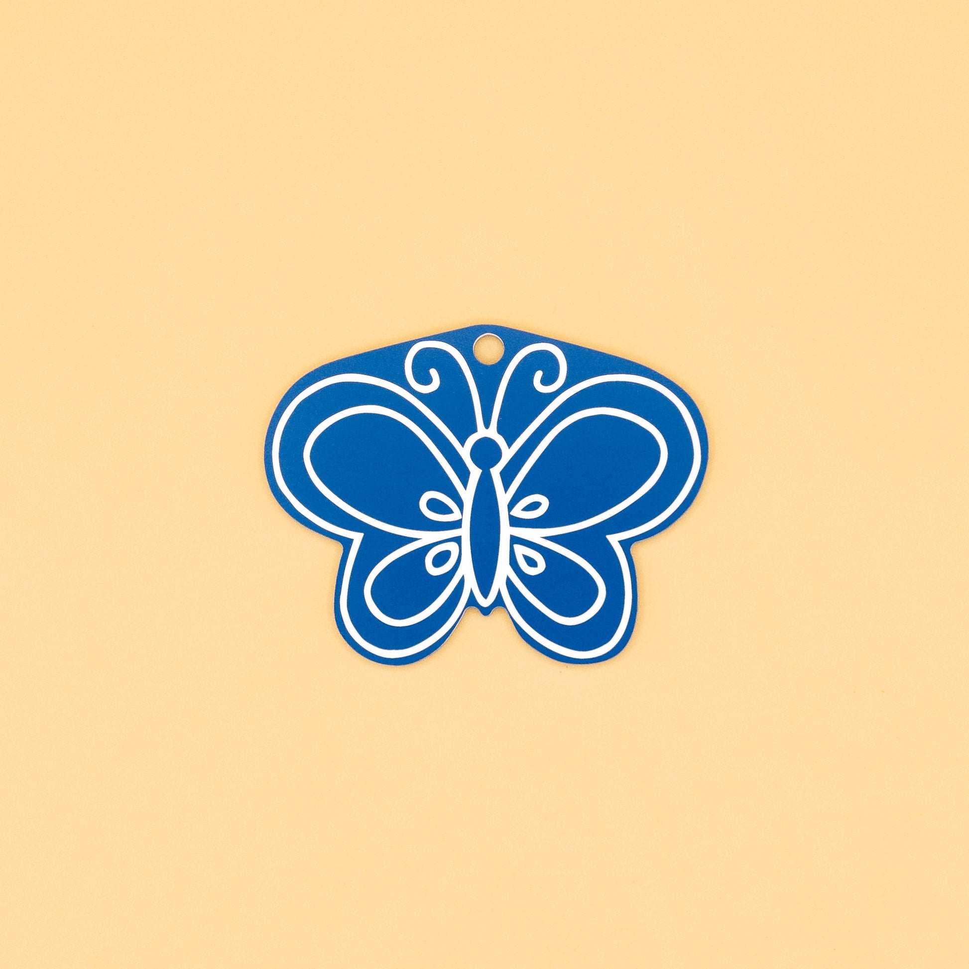 Blue butterfly-shaped keychain on a beige background