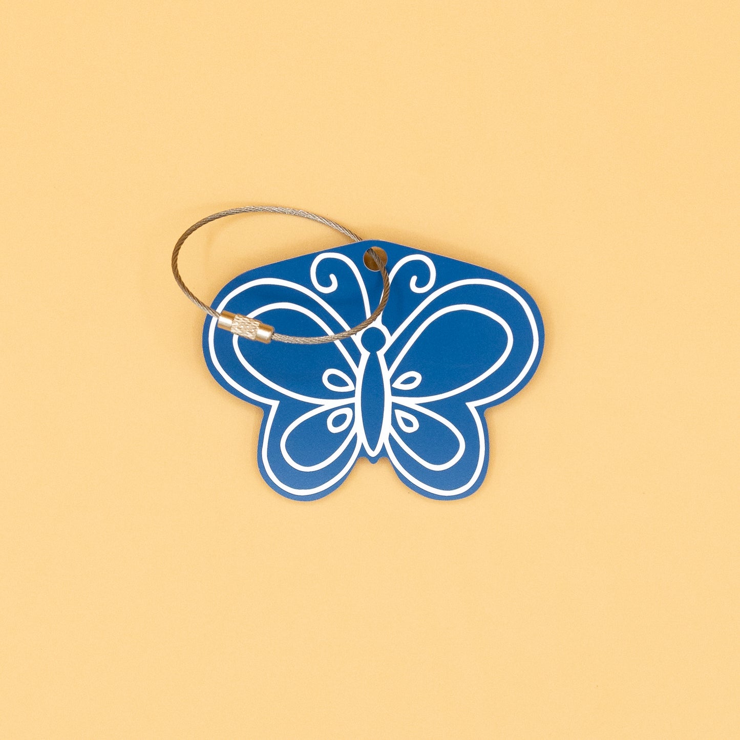 Blue butterfly-shaped keychain with a wire loop on a beige background