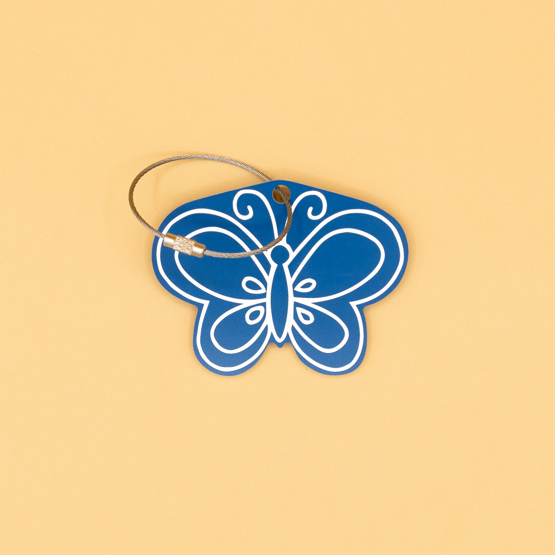 Blue butterfly-shaped keychain with a wire loop on a beige background