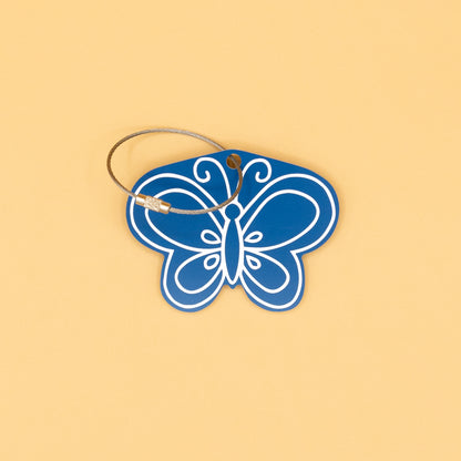 Blue butterfly-shaped keychain with a wire loop on a beige background