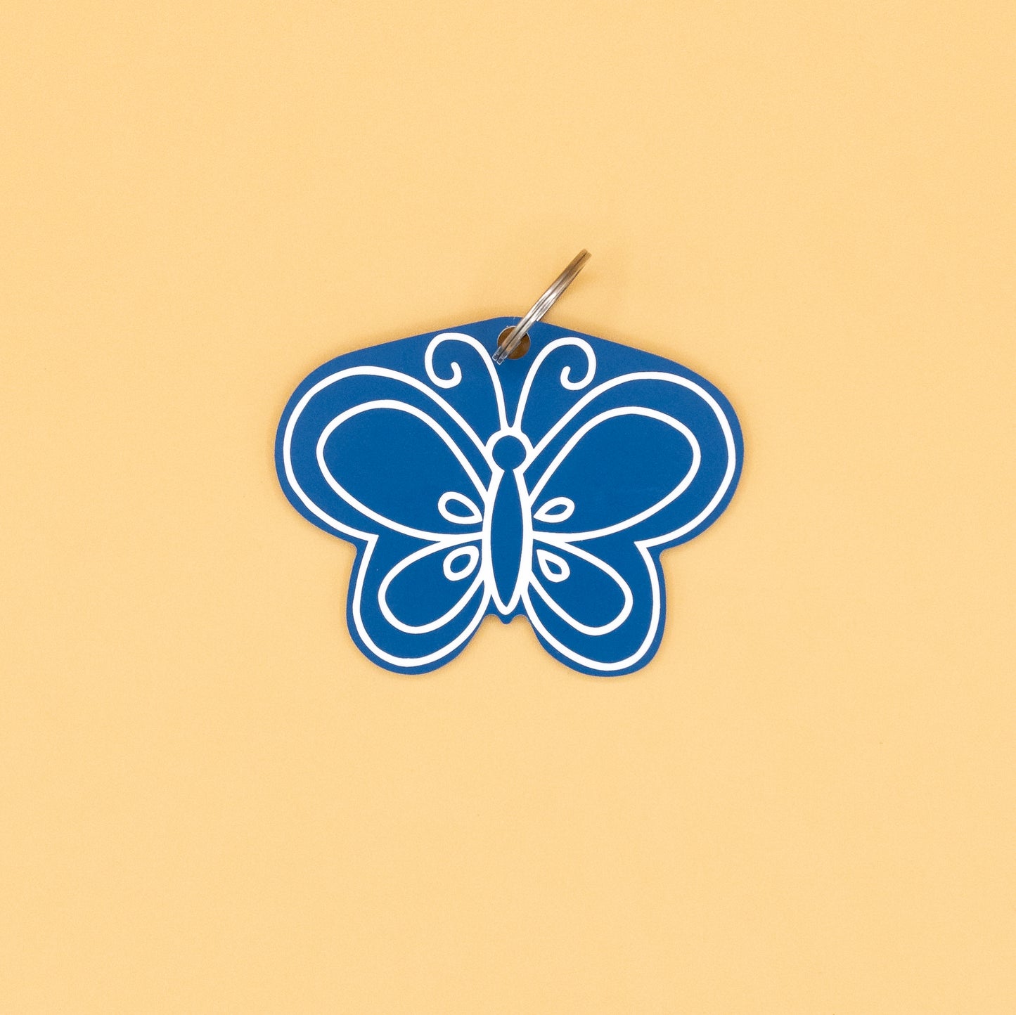 Blue butterfly-shaped keychain with classic key ring on a beige background