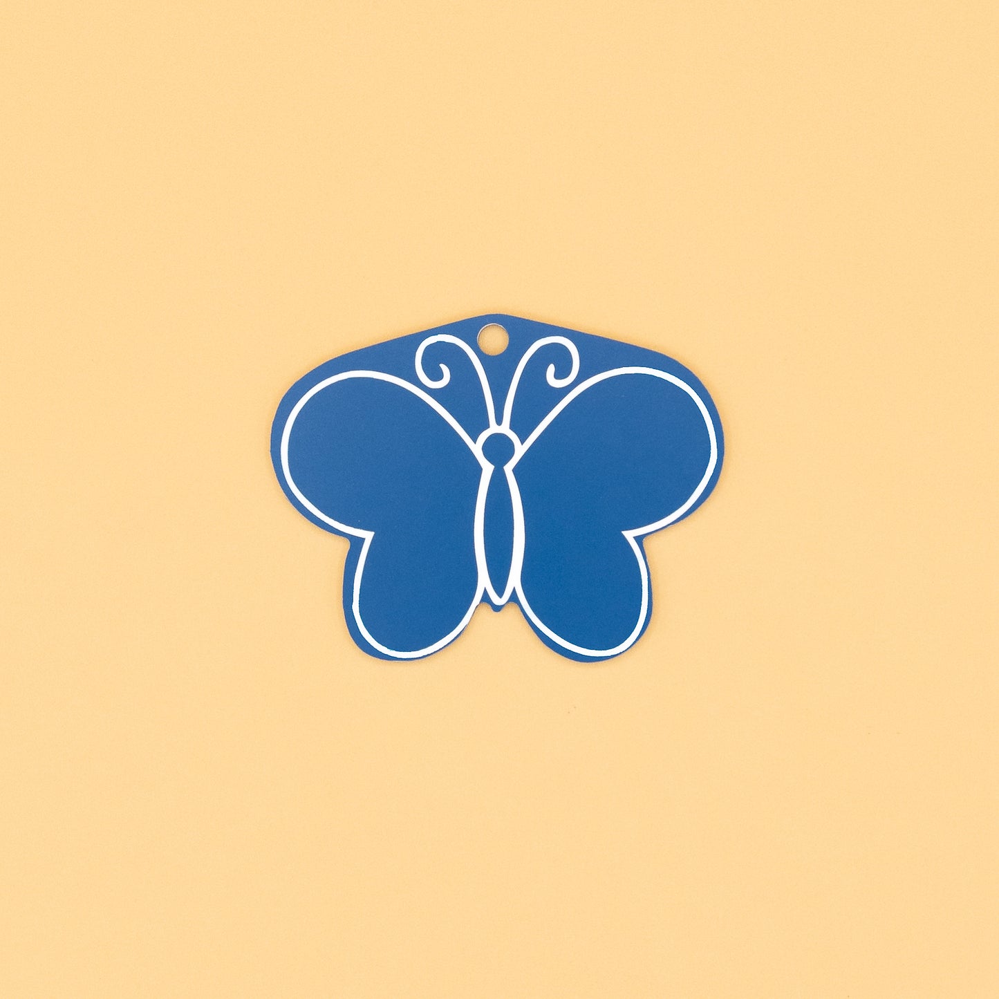 Rear of butterfly-shaped keychain on a beige background