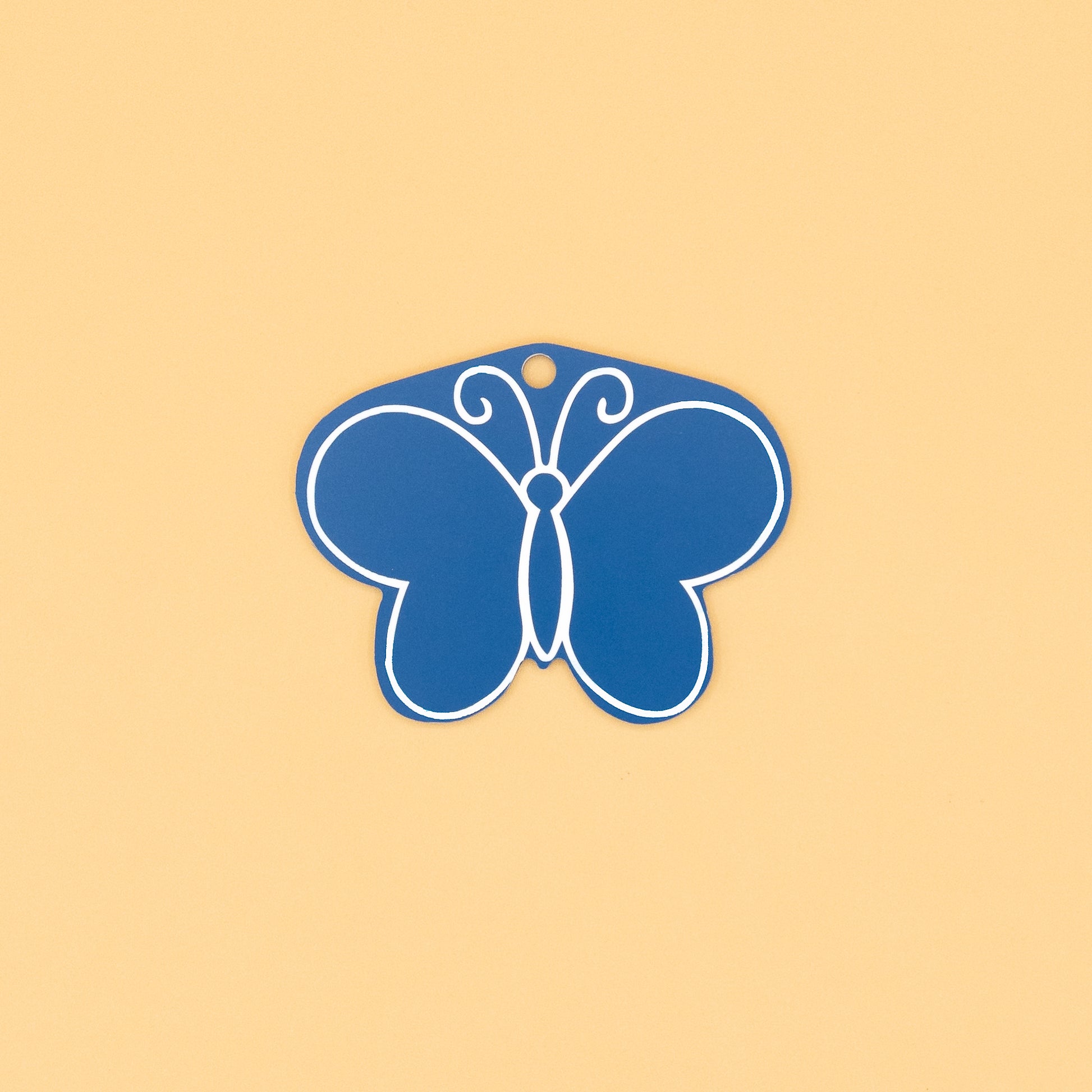 Rear of butterfly-shaped keychain on a beige background