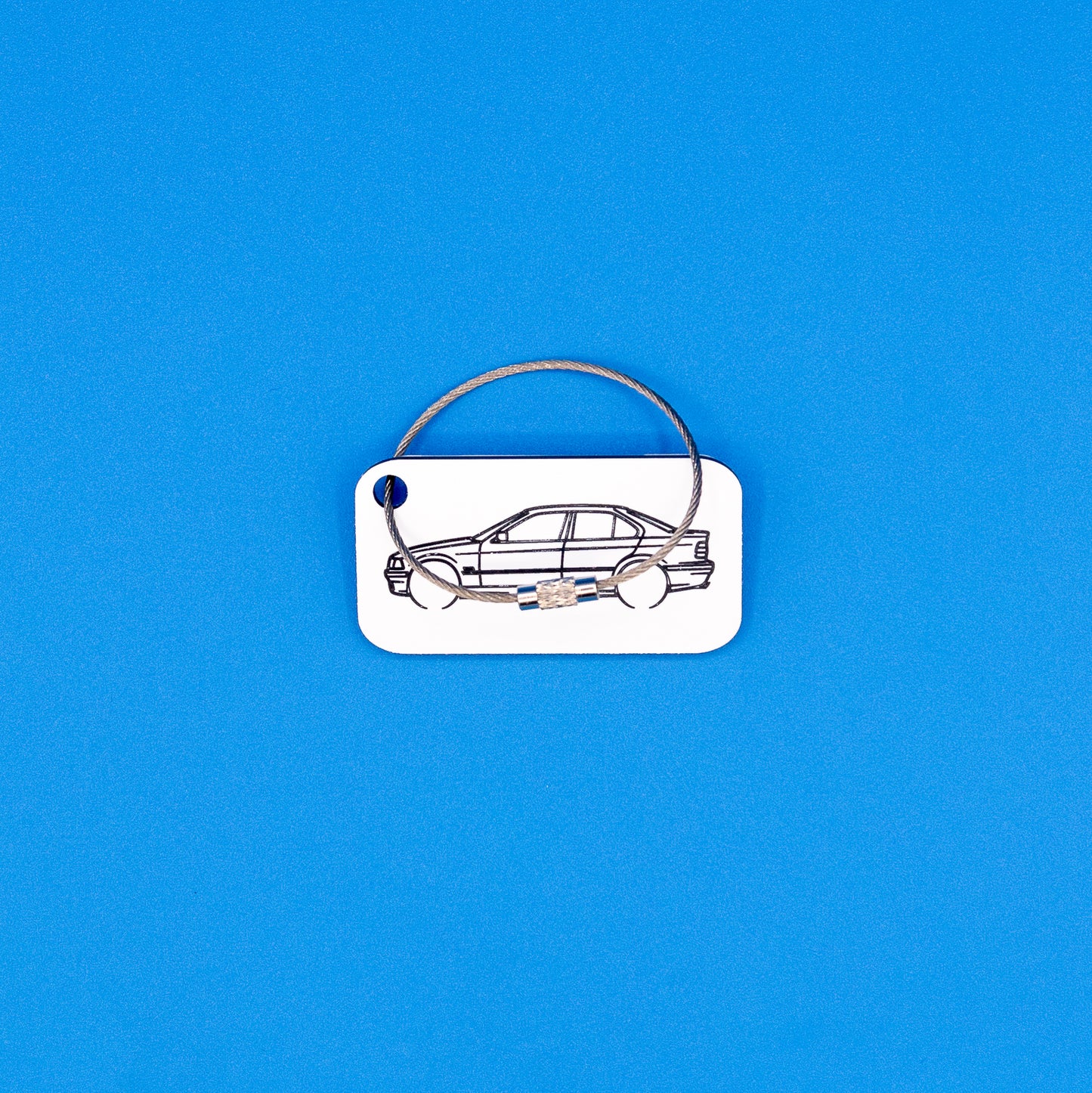 BMW E36 series sedan with wire loop keychain on a blue background