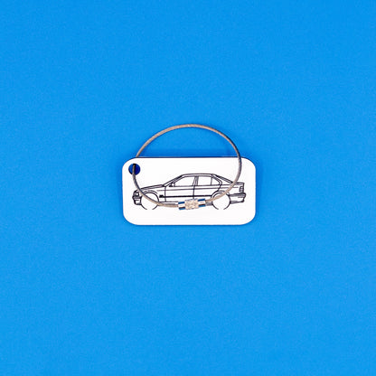 BMW E36 series sedan with wire loop keychain on a blue background