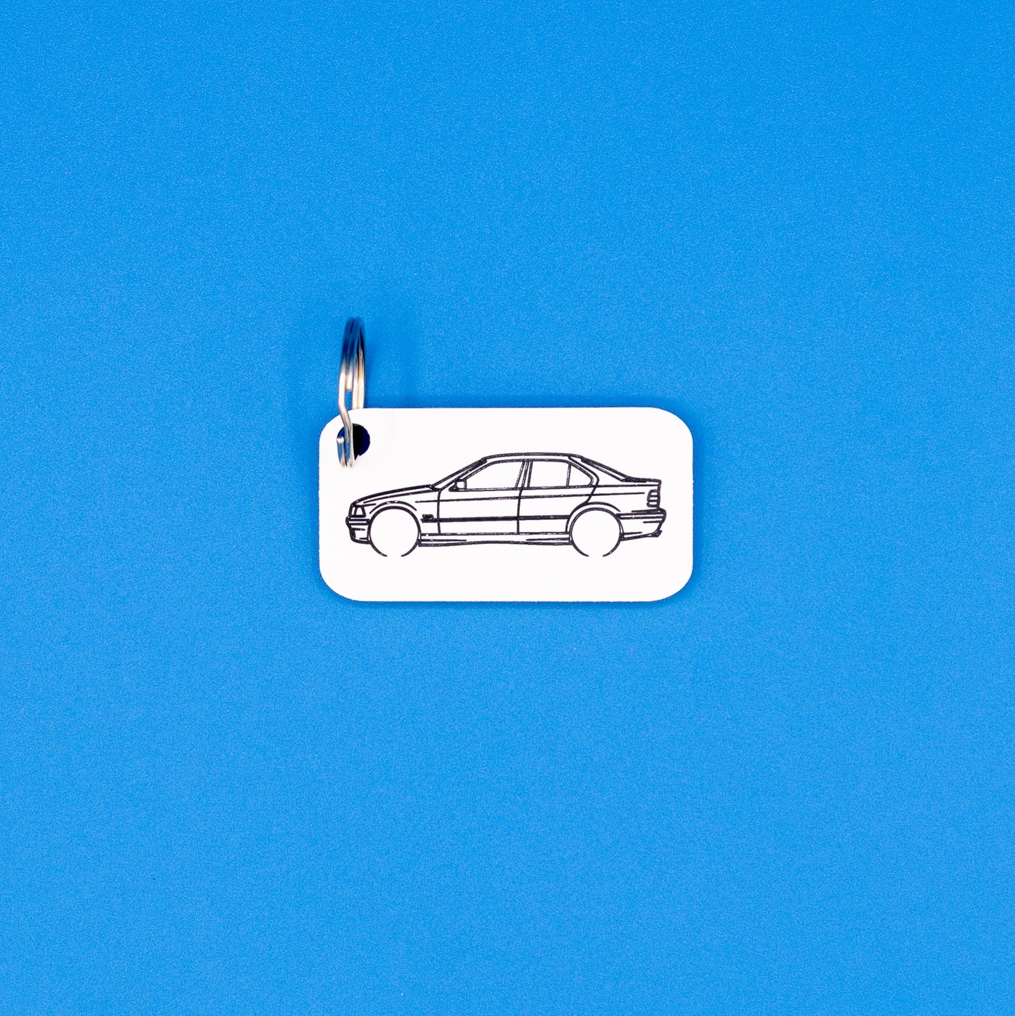 BMW E36 3 Series Sedan with key ring keychain on a blue background