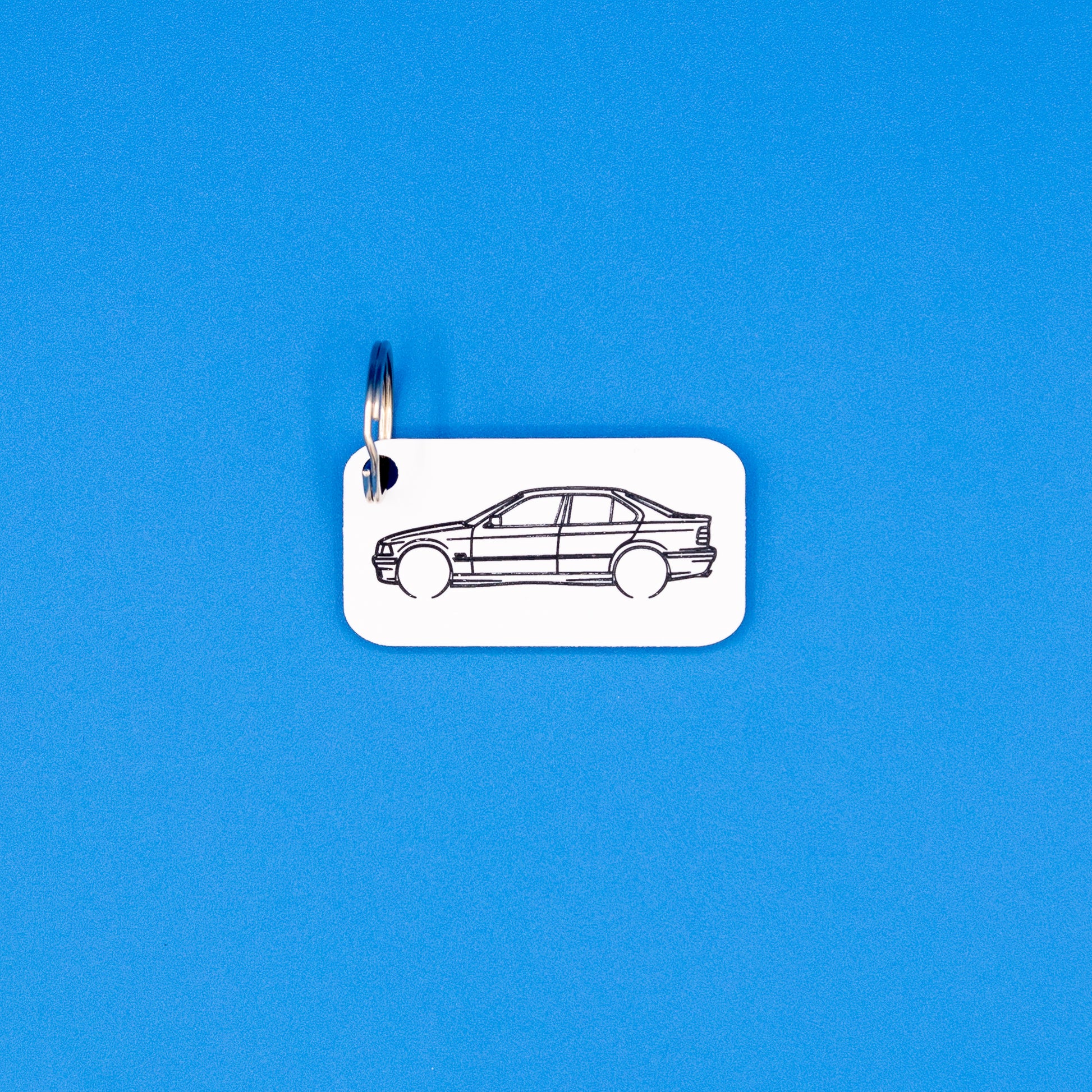 BMW E36 3 Series Sedan with key ring keychain on a blue background