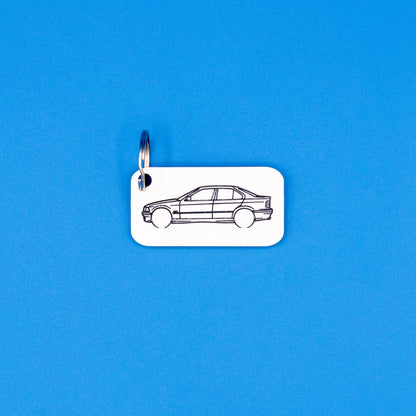 BMW E36 3 Series Sedan with key ring keychain on a blue background