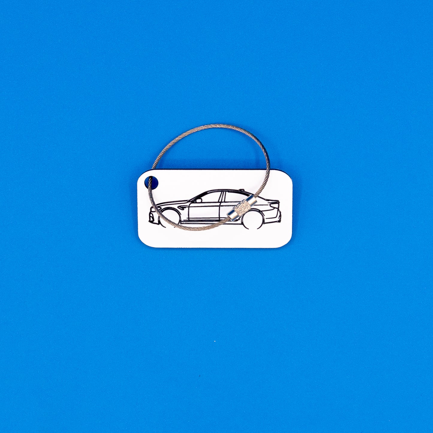 BMW F90 M5 keychain in white with wire loop on a blue background