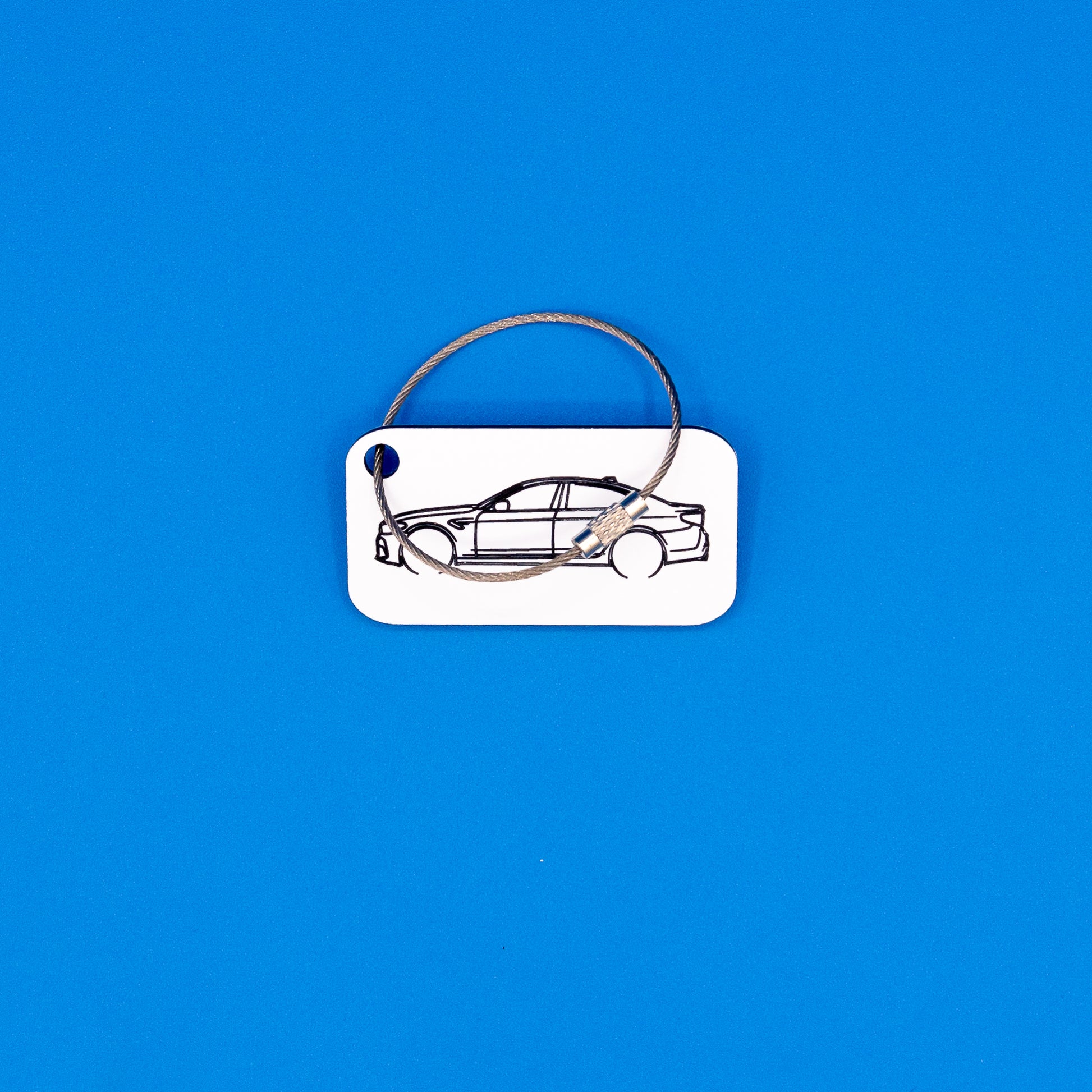 BMW F90 M5 keychain in white with wire loop on a blue background