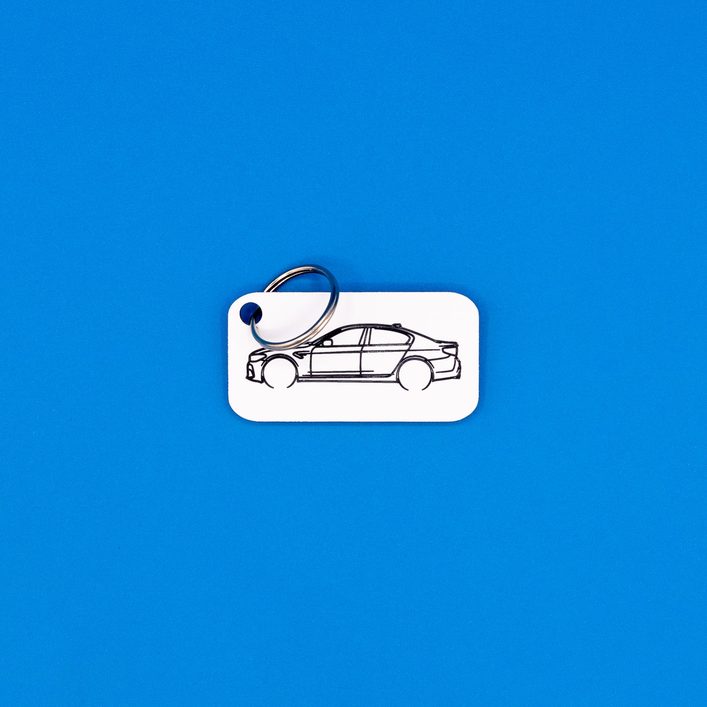 BMW F90 M5 keychain in white with classic key ring on a blue background