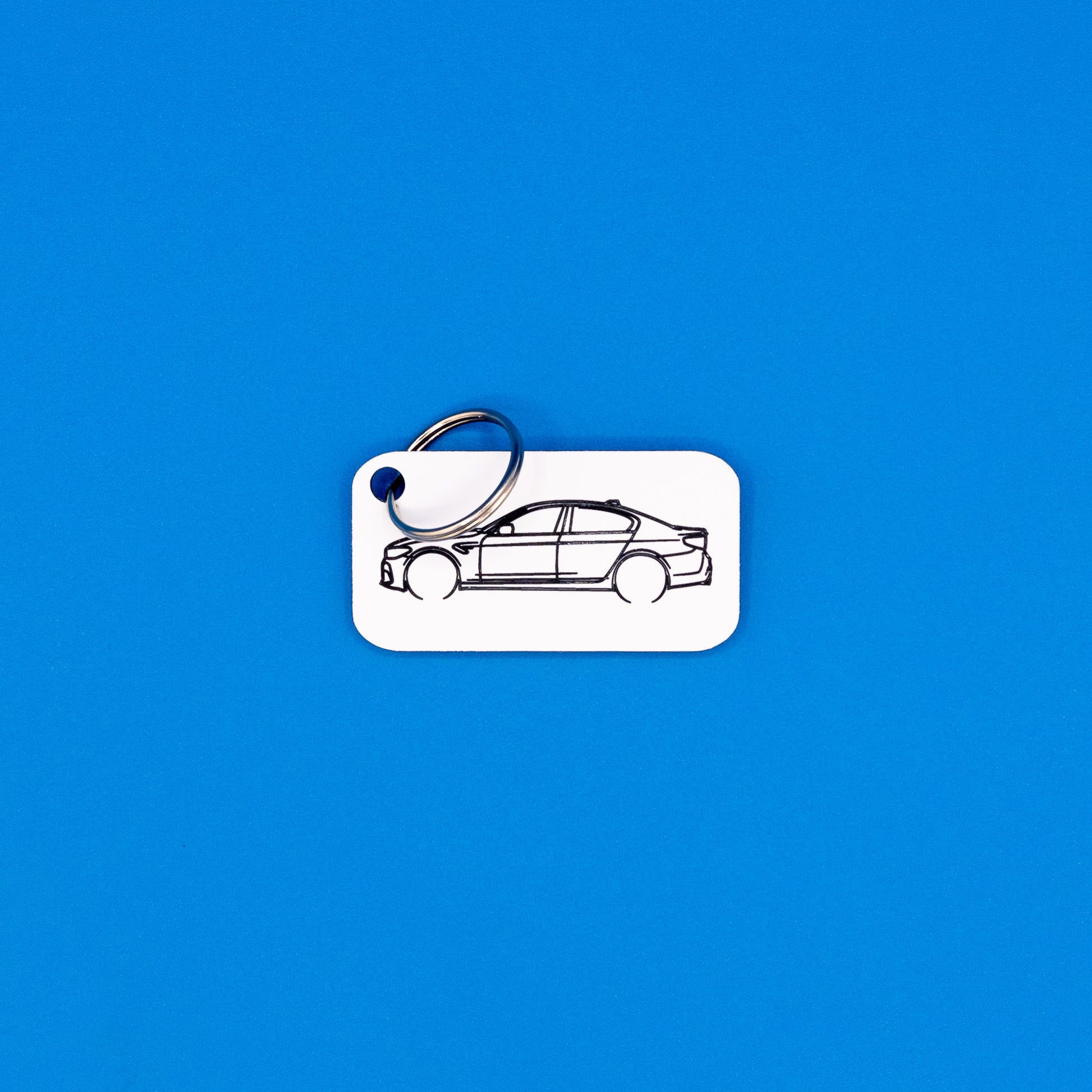 BMW F90 M5 keychain in white with classic key ring on a blue background