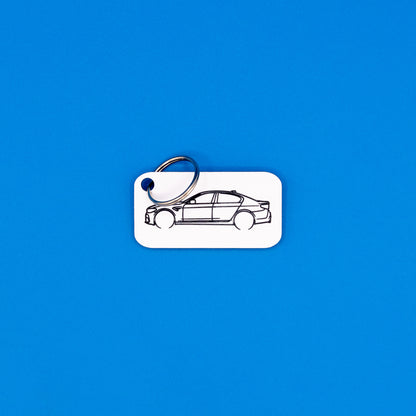 BMW F90 M5 keychain in white with classic key ring on a blue background