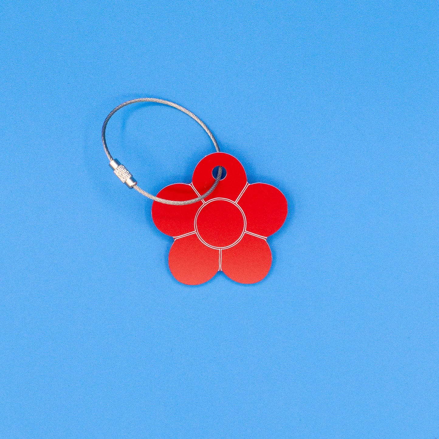 Red flower-shaped tag with a metal loop on a blue background