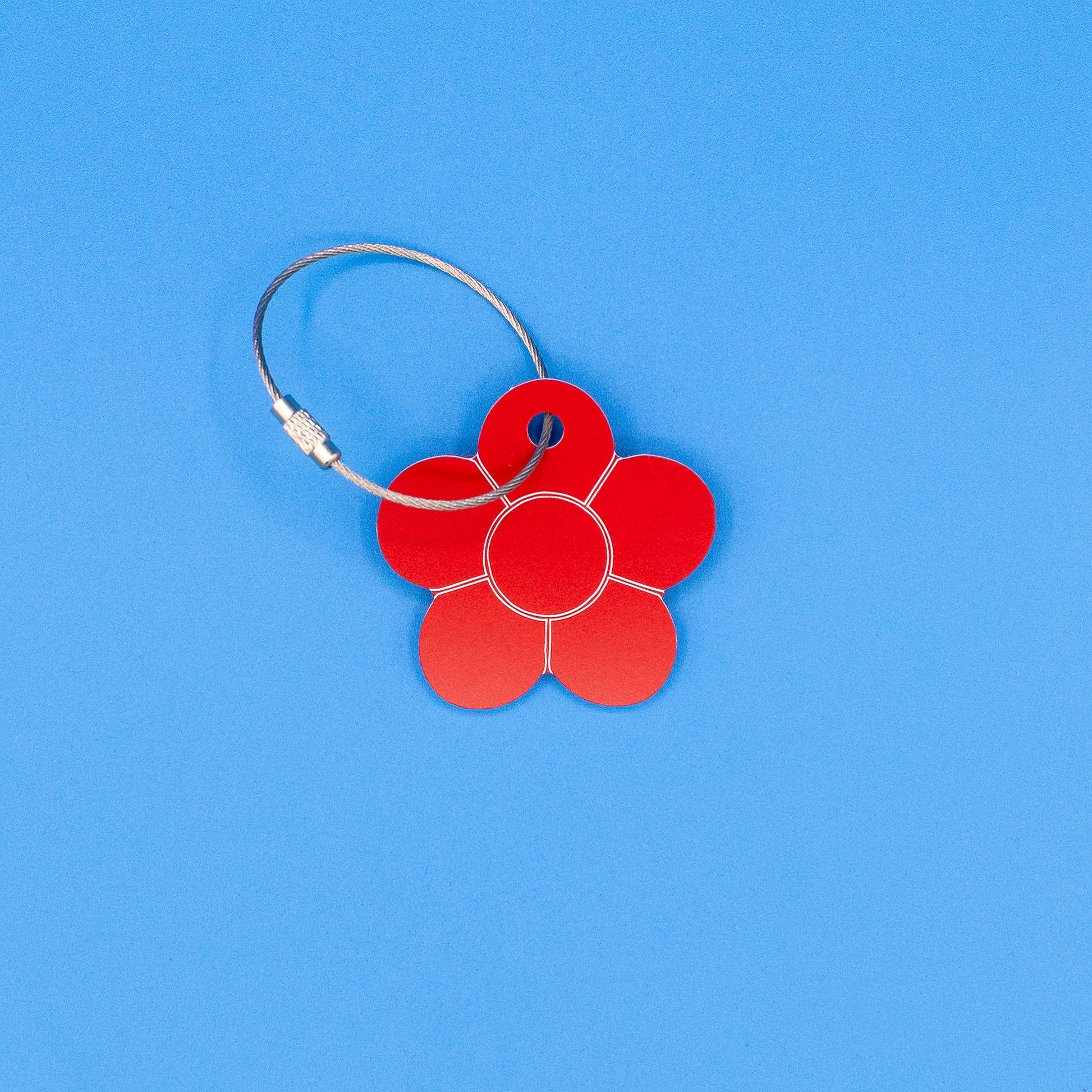 Red flower-shaped tag with a metal loop on a blue background