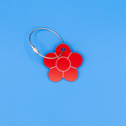 Red flower-shaped tag with a metal loop on a blue background
