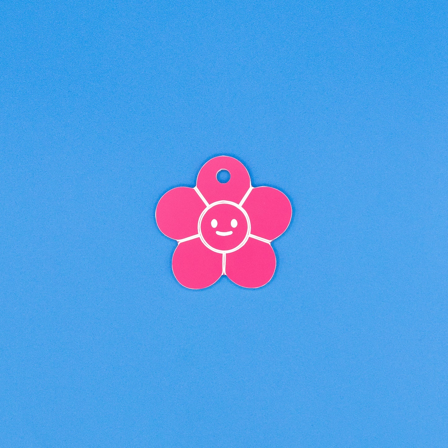 Pink flower-shaped tag with a smiley face on a blue background