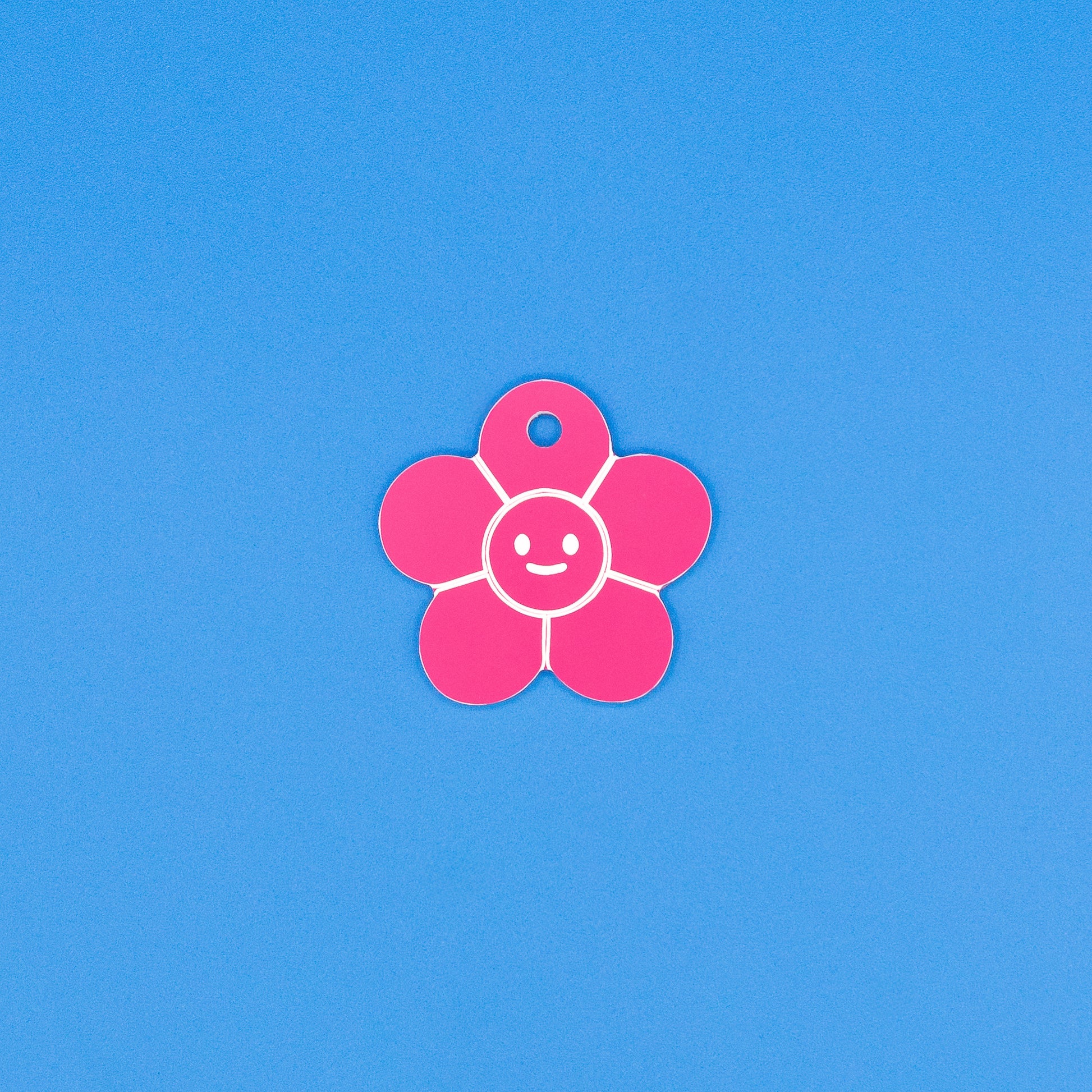 Pink flower-shaped tag with a smiley face on a blue background