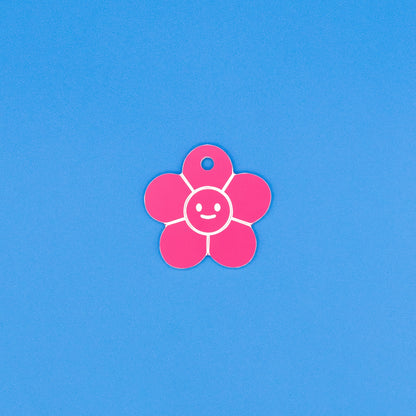 Pink flower-shaped tag with a smiley face on a blue background