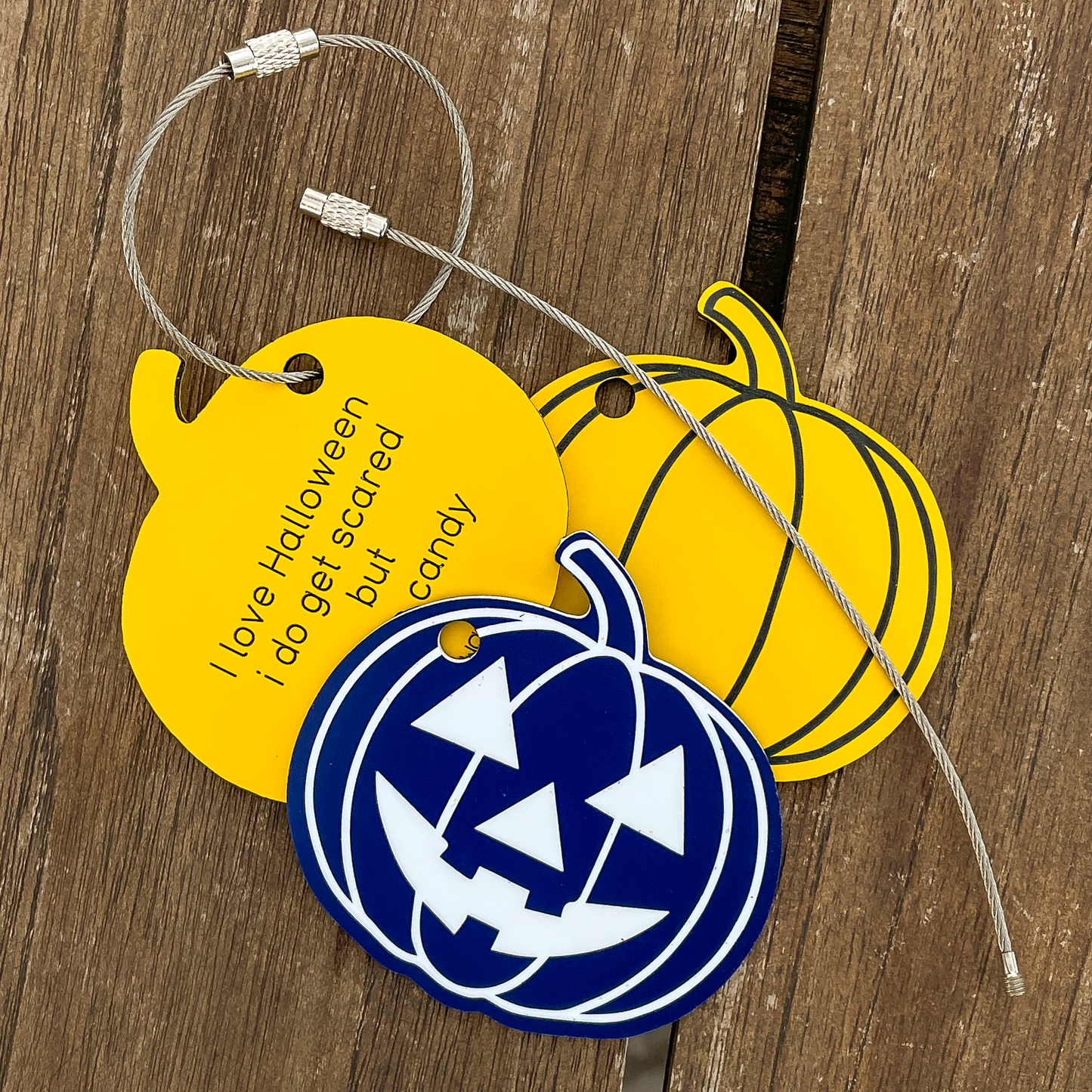 Three fall-themed keychains on a wooden surface.