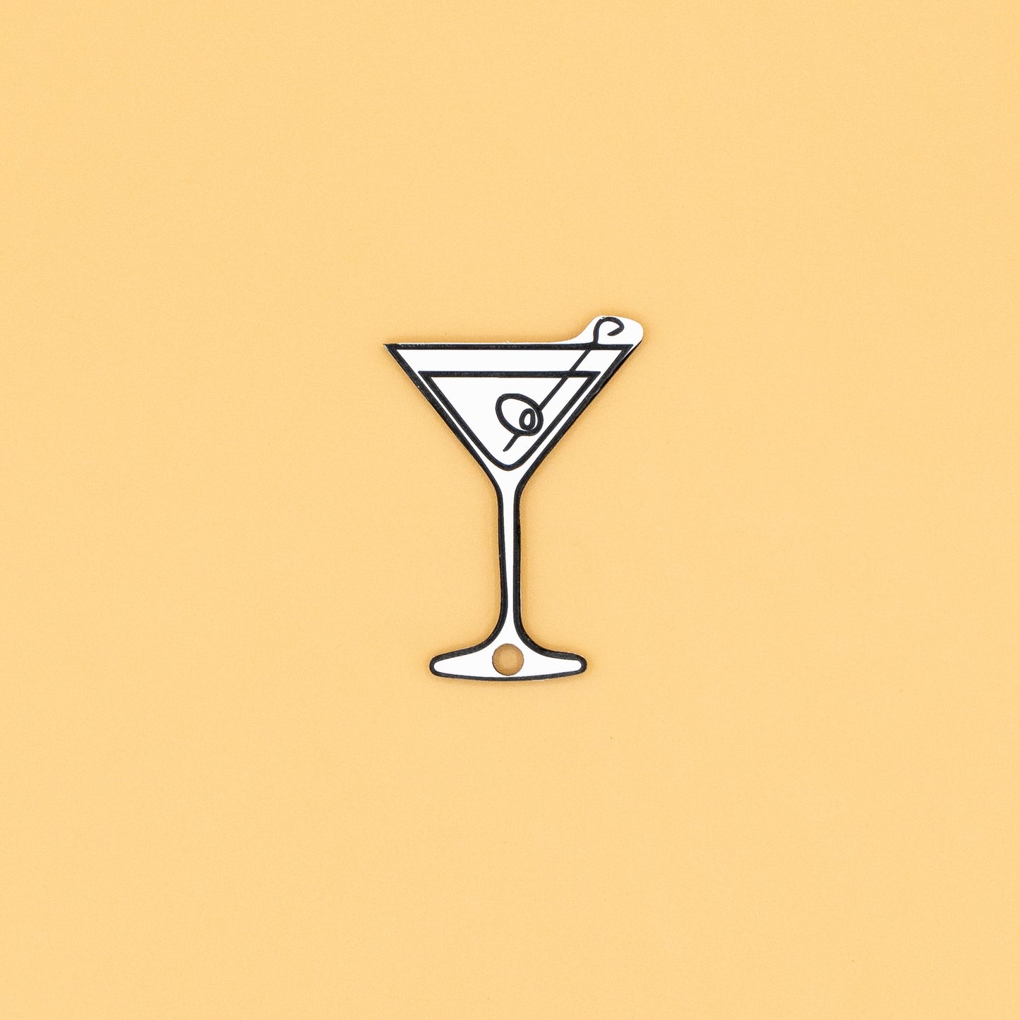 Illustration of a martini glass keychain with a olive on a beige background