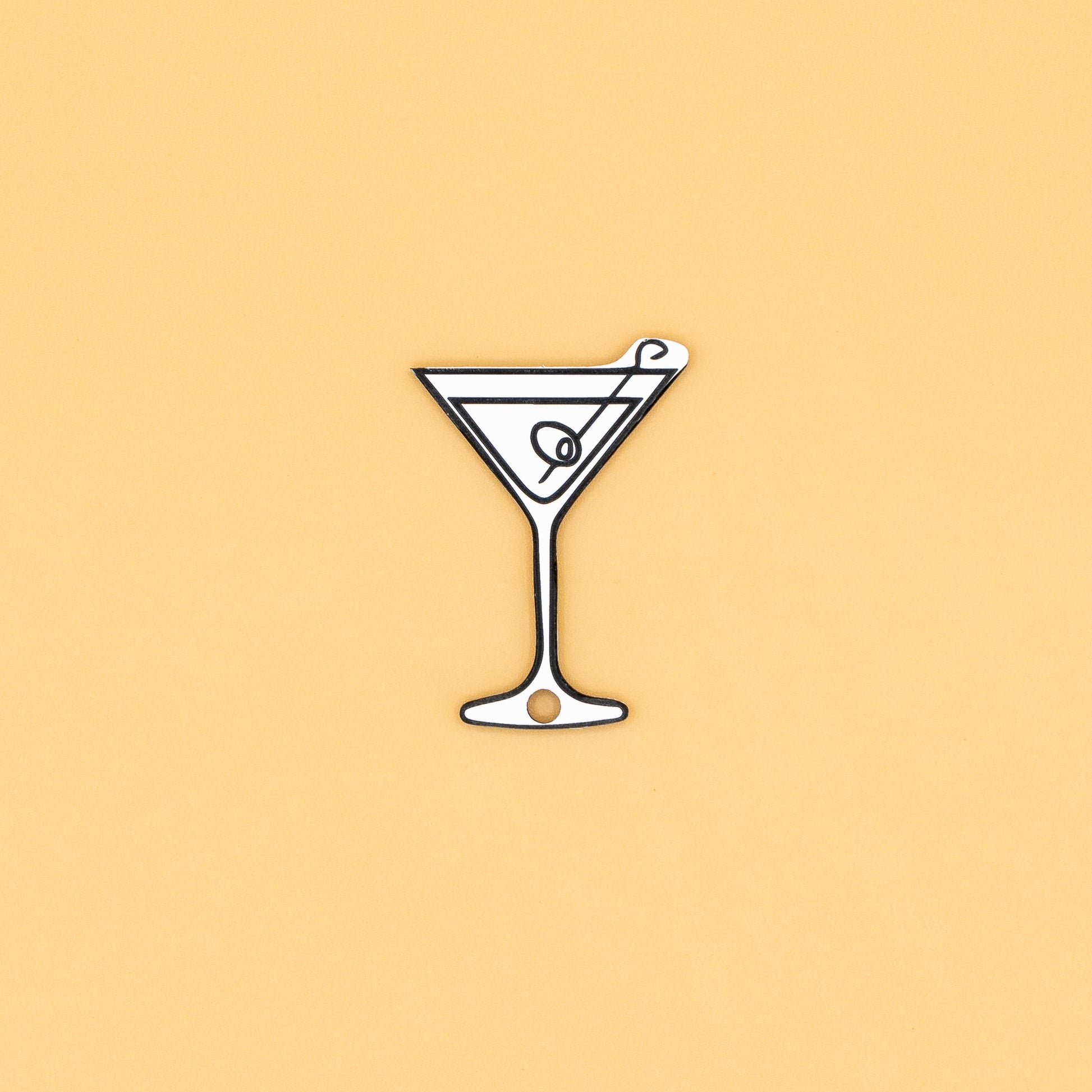 Illustration of a martini glass keychain with a olive on a beige background