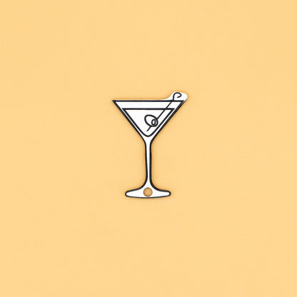 Illustration of a martini glass keychain with a olive on a beige background