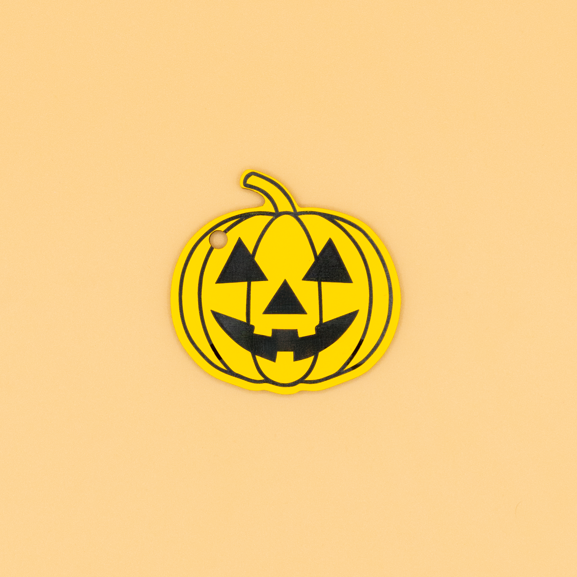 Pumpkin-shaped Halloween tag with black face design on a beige background