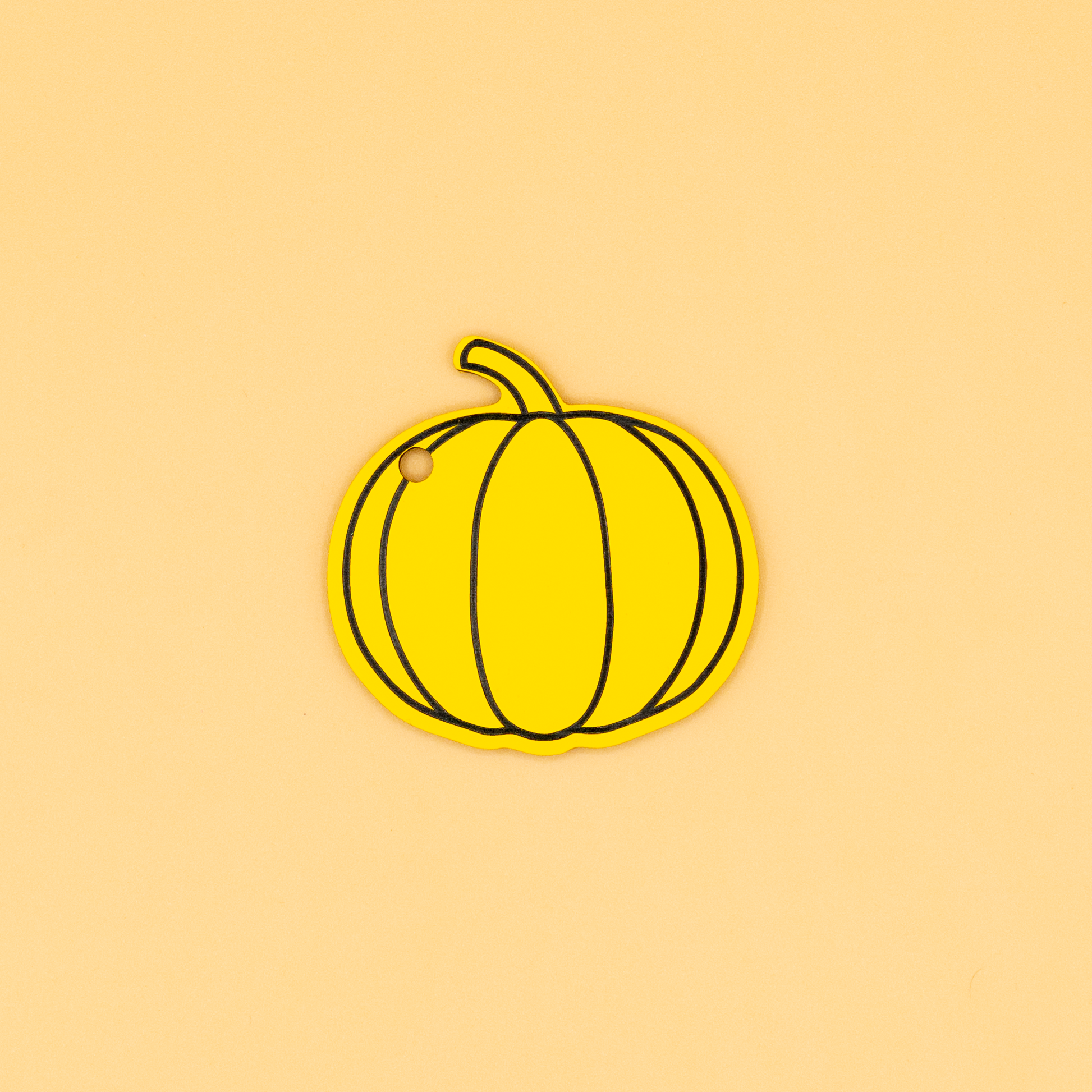 Yellow pumpkin keychain on a beige background