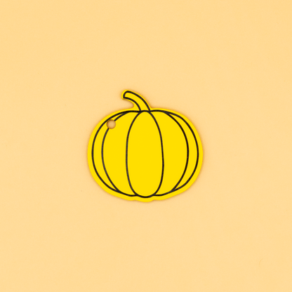 Yellow pumpkin keychain on a beige background