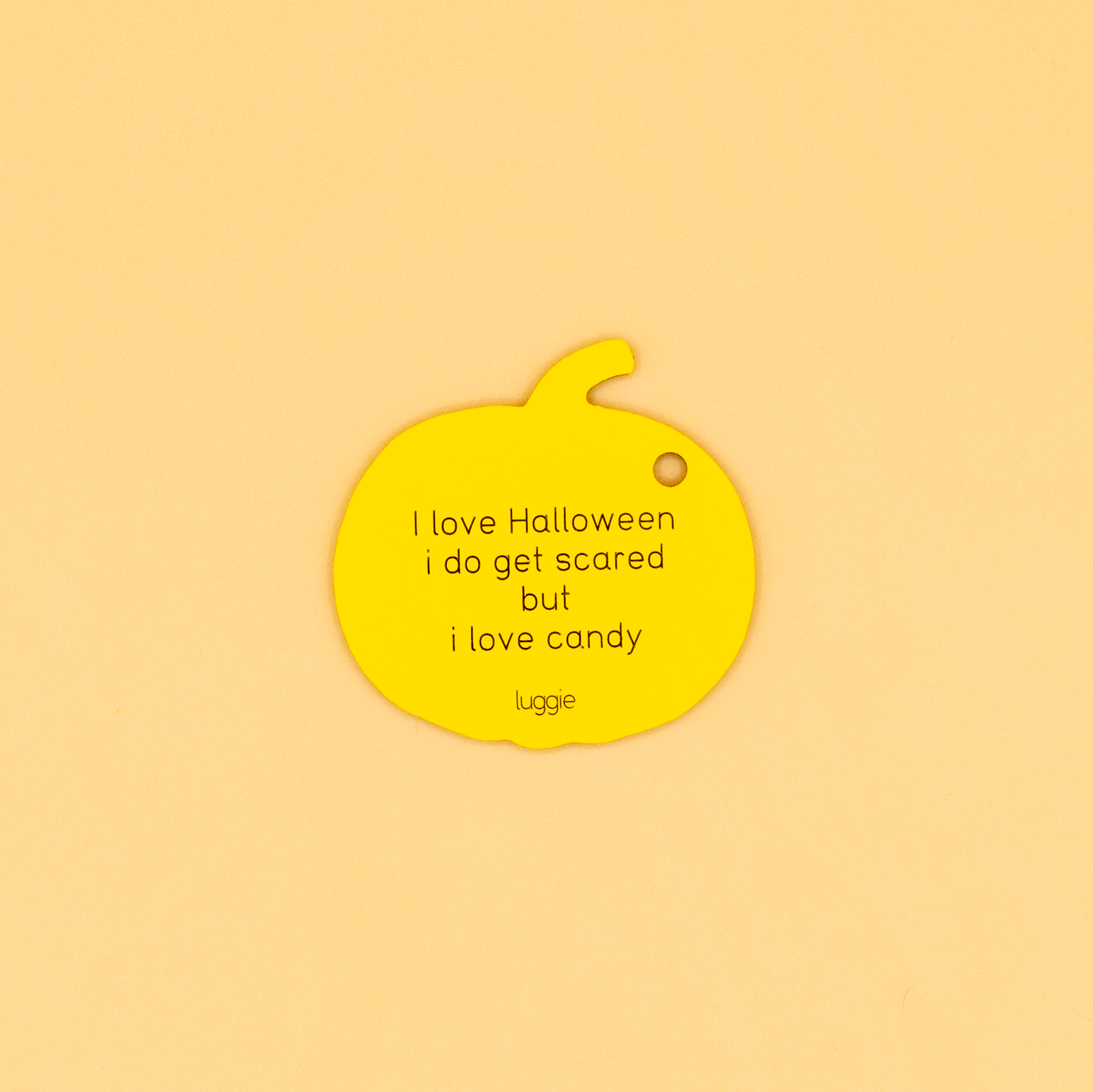 Yellow pumpkin-shaped keychain with text on a beige background