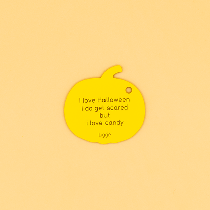 Yellow pumpkin-shaped keychain with text on a beige background