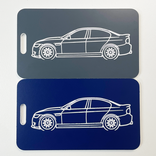Two car-shaped luggage tags, one gray and one blue, on a light gray background.